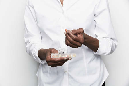 Mid section of senior woman taking tablet from medicine organiserの写真素材