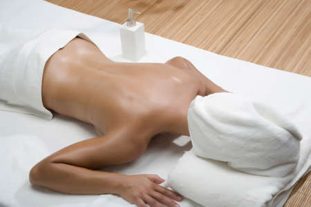 Woman lying in spa with towel covering headの写真素材