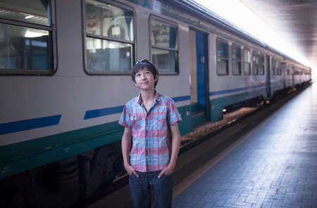 Boy by train with hands in pocketsの写真素材