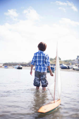 Portrait of boy playing with model boatの写真素材