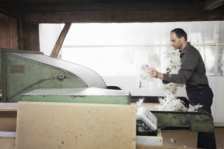 Man adding fleece to machine in wool factory
