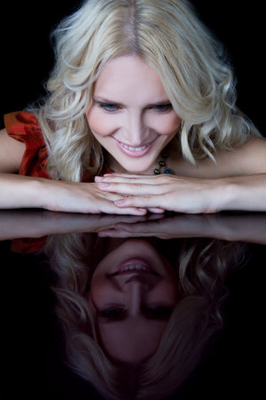 Woman looking at reflection of herself on tableの写真素材
