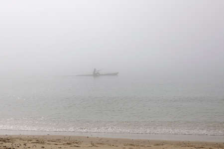 Sea kayaker on misty sea, Poole, Dorset, UKの写真素材
