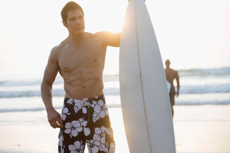 Man holding surfboard on beachの写真素材
