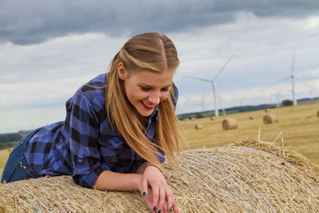 Portrait of young woman leaning over straw baleの写真素材