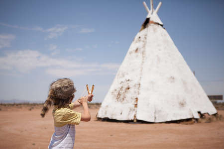 Boy aiming slingshot at teepee, Indian Reservation, USAの写真素材