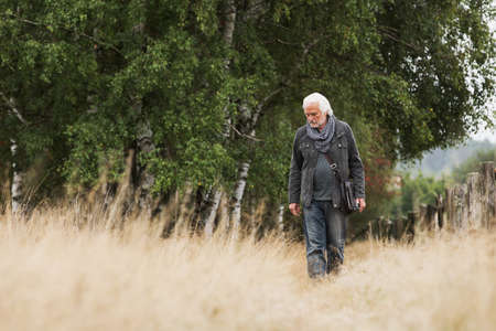 Senior man walking in meadowの写真素材