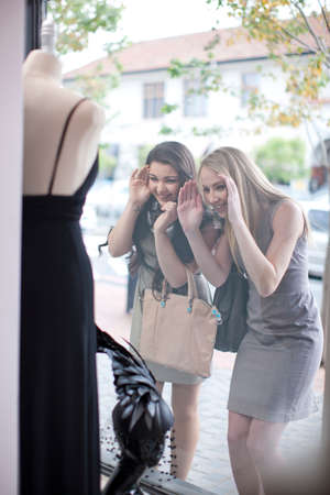 Friends window shopping, looking through shop frontの写真素材