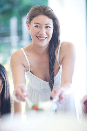 Portrait of young woman serving meal to friendsの写真素材
