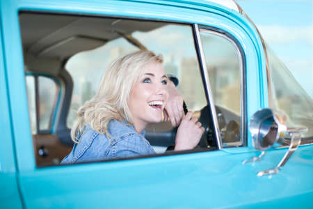 Woman at wheels of vintage car looking up from windowの写真素材