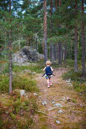 Rear view of girl carrying rucksack through forestの写真素材