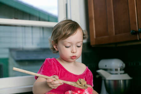 Girl with wooden spoon of cookie doughの写真素材