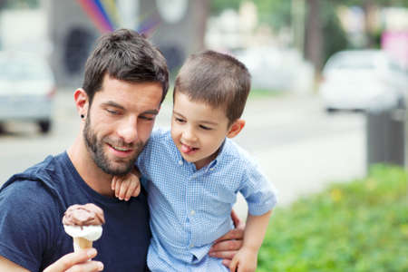 Father holding ice cream, son licking lipsの写真素材