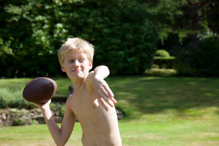 Boy in garden throwing rugby ballの写真素材