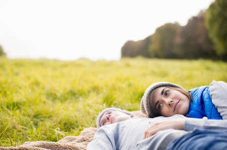 Young woman resting head on man's chest in parkの写真素材