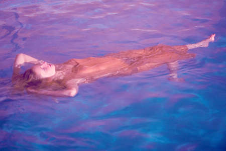 Young woman swimming underwater in pool in underwearの写真素材