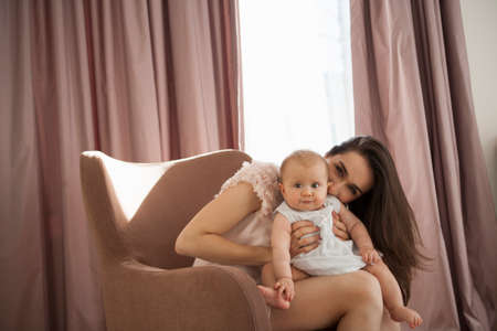 Mother playing with baby in armchair