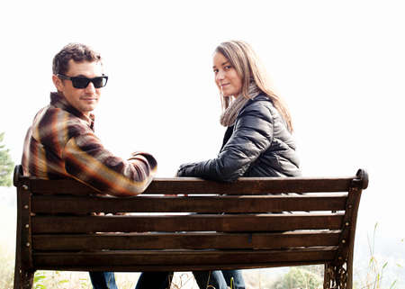 Couple sitting on park bench and looking over their shoulderの写真素材