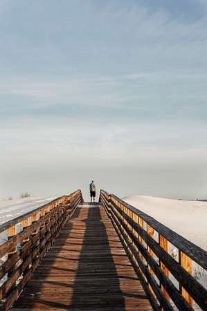 Young man on elevated wooden walkway, Gulf Coast, Alabama, USAの写真素材