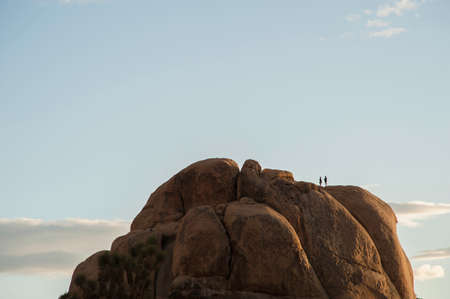 Two people on high rock formation, Joshua Tree national park, California, USAの写真素材