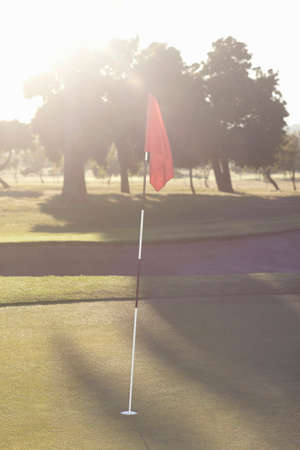 Golf flag on golf course green at sunriseの写真素材