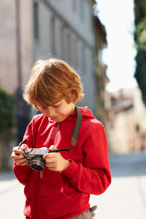 Young boy checking photographs on street, Province of Venice, Italyの写真素材