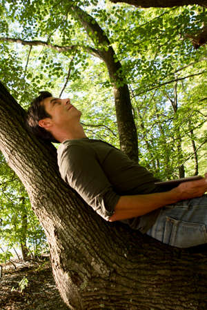 Mature man reclining on tree trunk in forestの写真素材