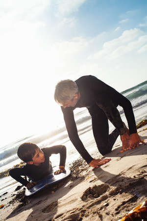 Father and son practicing on surfboard at beach, Encinitas, California, USAの写真素材