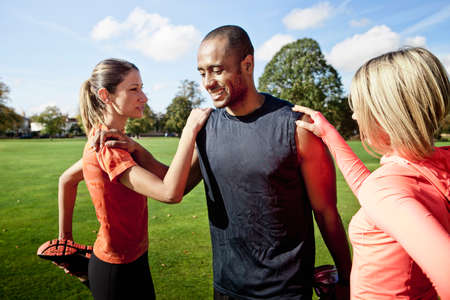 Man and women stretching legs in park