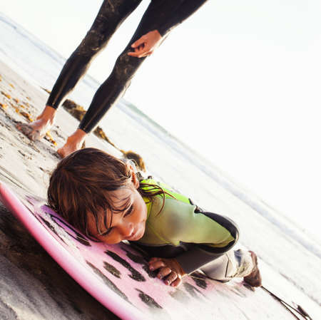 Father and daughter learning surfing on beach, Encinitas, California, USA