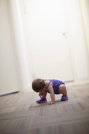 Toddler girl crouching on floorの写真素材
