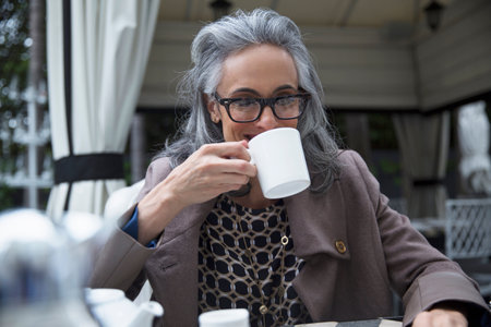 Mature woman drinking coffee on luxury porchの写真素材