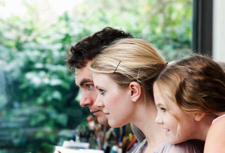 Close up of girl and parents at home staring at computer