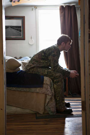 Teenage boy sitting on sofa concentrating on video gameの写真素材