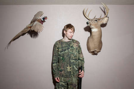 Home portrait of teenage boy holding shotgunの写真素材