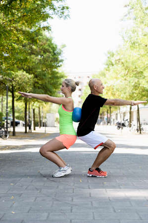 Young woman and trainer using exercise ball in park