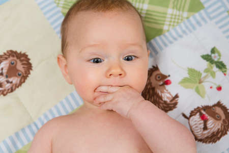 7 month old baby girl in crib with fingers in her mouth