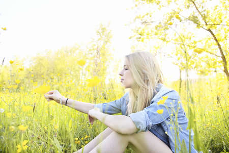 Young woman sitting in field with wildflowers