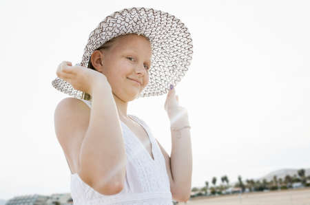 Portrait of girl holding her sunhat on beach