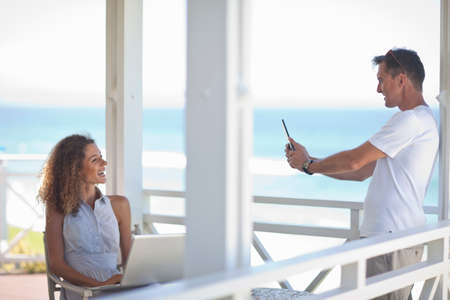 Couple taking photographs on beach house balconyの写真素材