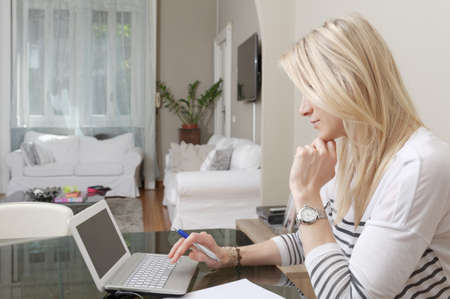 Young woman typing on laptop at home deskの写真素材