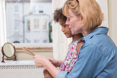 Mother and daughter looking at hand-held fanの写真素材