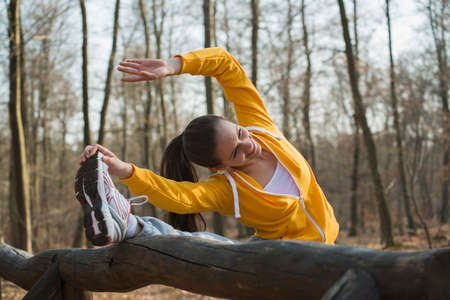 Young woman touching toes on assault course in forestの写真素材