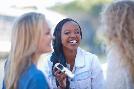 Three young female friends with smartphone laughing