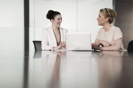 Two young businesswomen having face to face meeting in conference roomの写真素材