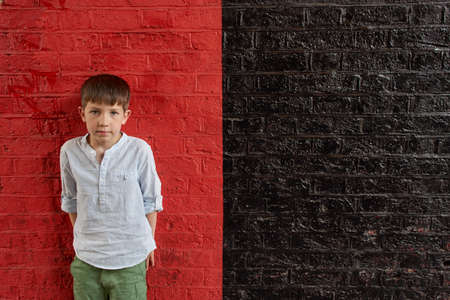 Boy against red and black wallの写真素材