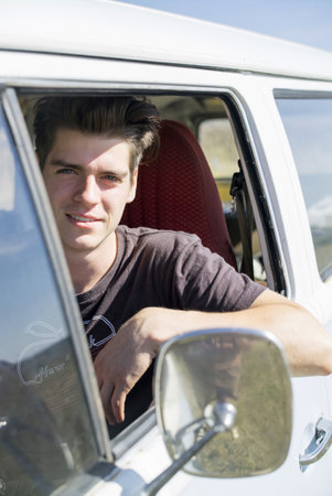 Young man in campervan, looking at camera
