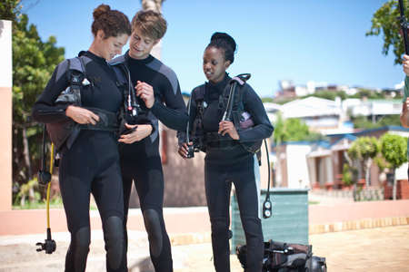 Scuba diving instructor strapping equipment onto pupil