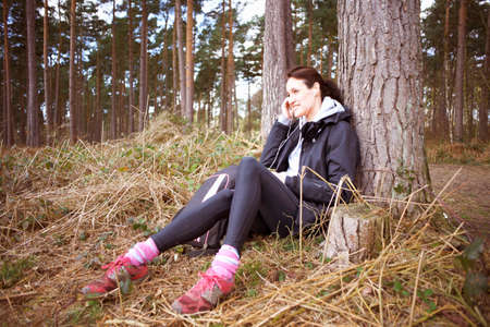 Mature woman runner talking on her cellphone in a forestの写真素材