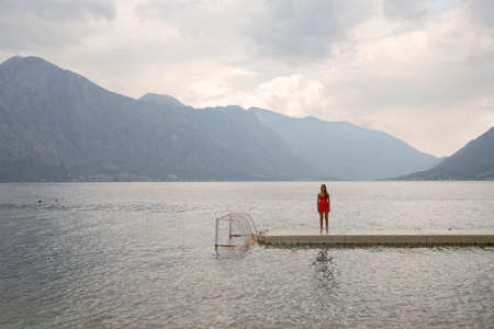 Solitary young woman standing on pier, Bajova Kula, Montenegroの写真素材